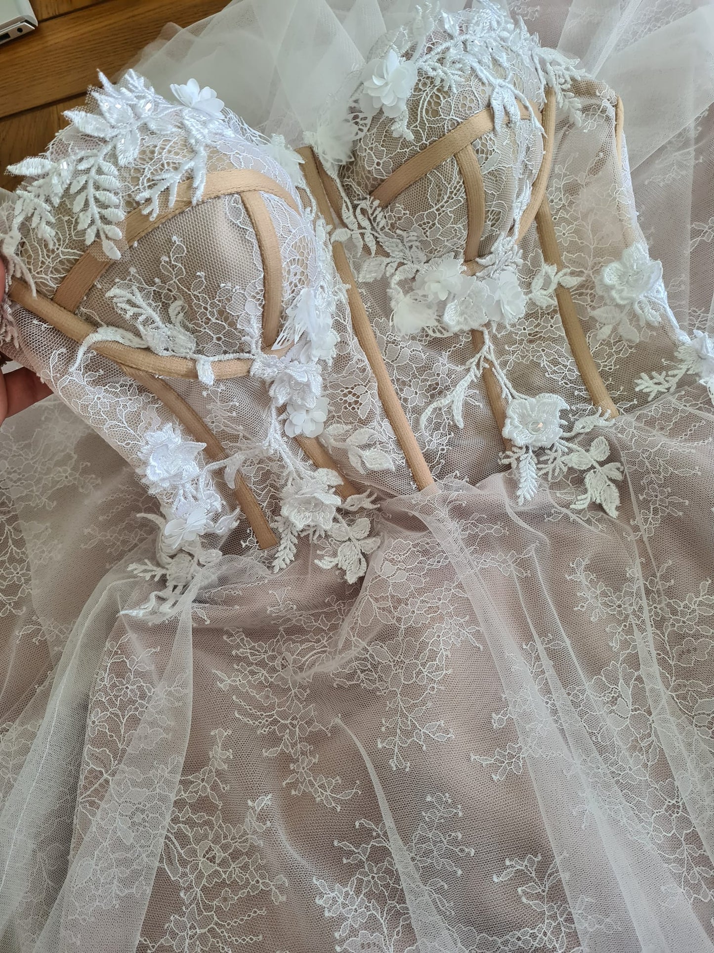 Beautiful wedding dress with a sheer cupped bustier, delicate ivory lace overlay and 3D floral lace hand applique detail. The dress has a nude colour satin lining, overlaid with delicate lace and a layer of soft flowing tulle. The dress has a lace up ribbon corset back and concealed zipper in the skirt