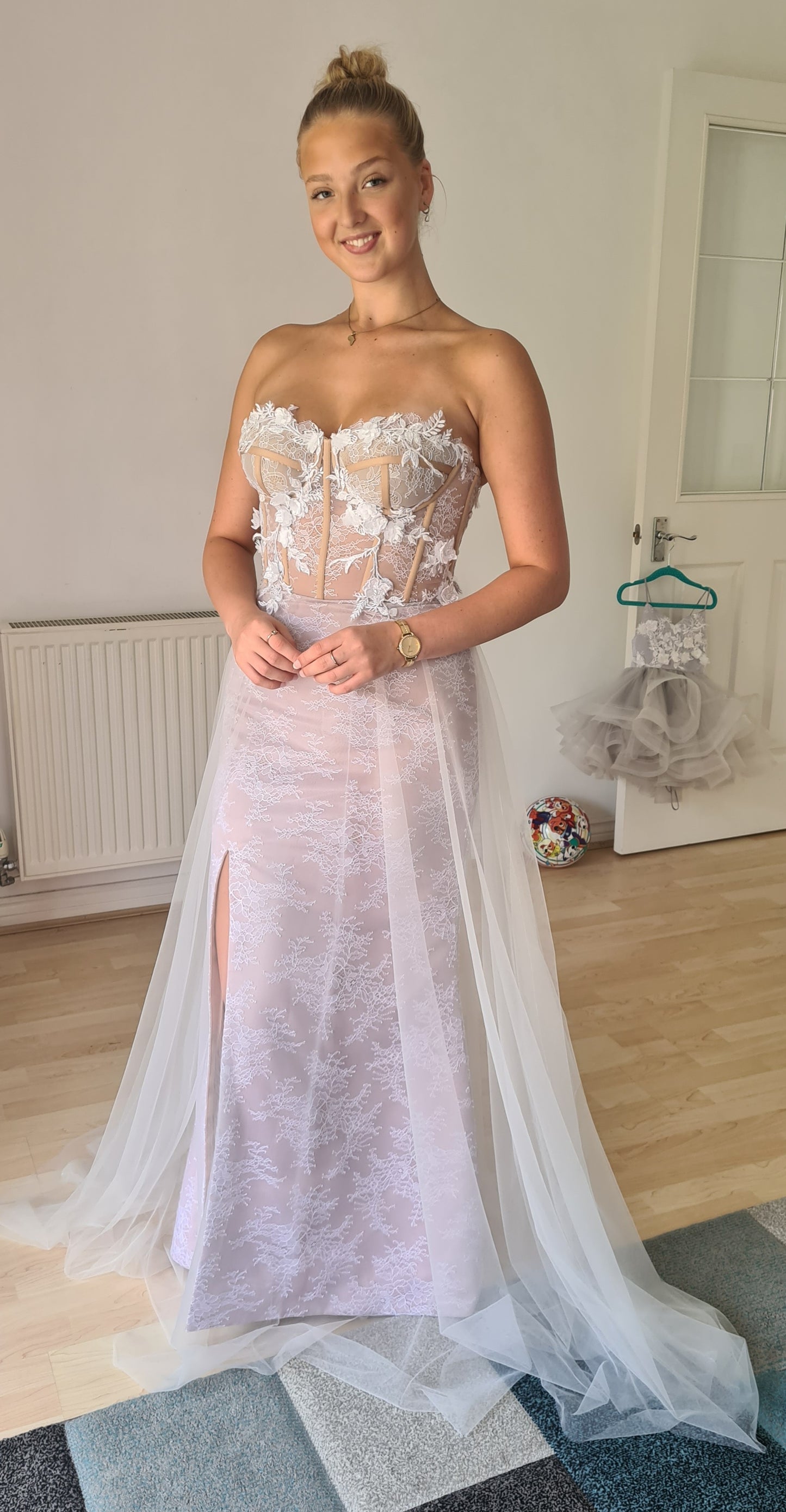 Beautiful wedding dress with a sheer cupped bustier, delicate ivory lace overlay and 3D floral lace hand applique detail. The dress has a nude colour satin lining, overlaid with delicate lace and a layer of soft flowing tulle. The dress has a lace up ribbon corset back and concealed zipper in the skirt